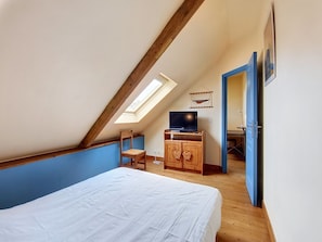 A bedroom with a sloped ceiling, a bed, a TV, and a wardrobe. - Vacation home Ty Coz by Interhome (Pleurtuit)