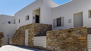 A modern building with a stone facade, a white exterior, and a door labeled "estia". - Villa Erato in Triantaros Tinos (Tinos island)