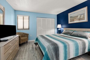 A bedroom with a bed, a TV, a chair, a dresser, and a painting on the wall. - Oceanfront condo overlooking sweeping sands & awesome views w/beachfront pool, expansive balcony (North Myrtle Beach)
