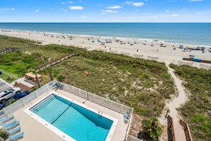 A beach resort with a swimming pool, beach chairs, and umbrellas. - Oceanfront condo overlooking sweeping sands & awesome views w/beachfront pool, expansive balcony (North Myrtle Beach)