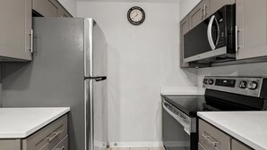 Eine kompakte Küche mit Kühlschrank, Mikrowelle, Backofen und Geschirrspüler.