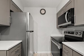 Un angolo cottura funzionale dotato di frigorifero, microonde, forno e lavastoviglie.