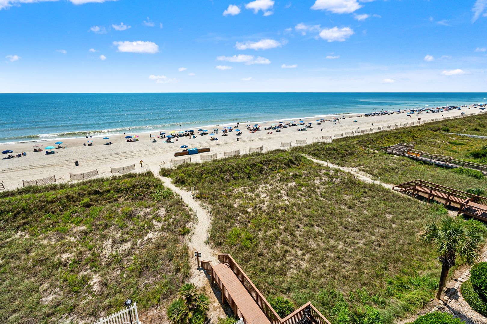 A beach with a wooden walkway and a fence.