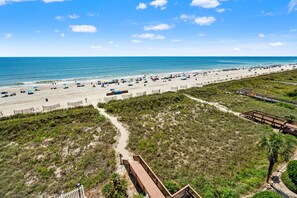Una spiaggia con una passerella in legno e una recinzione.