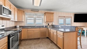 Una cocina con armarios de madera, encimeras de granito, horno empotrado, microondas y ventana con vistas.