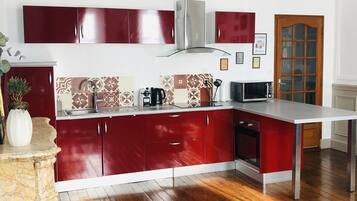 Une cuisine moderne avec des meubles de couleur rouge, un îlot en marbre et un plancher en bois.