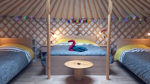 Una yurta acogedora con dos camas, una mesa central y luces de colores.
