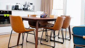 A modern kitchen with white cabinets, a wooden dining table, and four brown chairs.