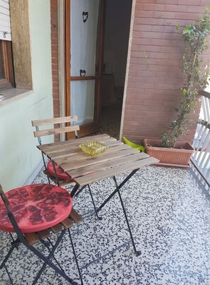 Enjoy a peaceful moment in this serene outdoor seating area with a table, chair, and lush greenery.