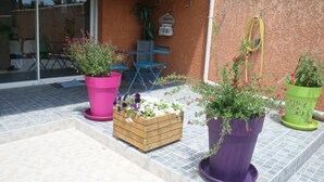 Eine Terrasse mit Blumentöpfen, einer Holzkiste und einem blauen Stuhl.
