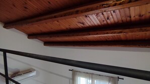 Un plafond en bois avec des poutres apparentes et une rambarde en métal noir.