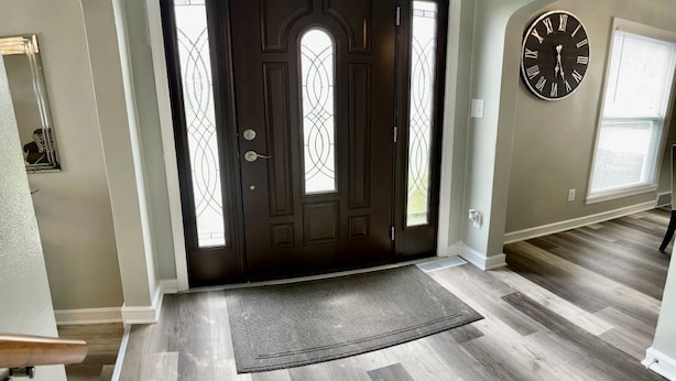 A modern entryway with a dark wooden door, a large wall clock, and a textured doormat. - NEW REMODEL! ARCADE GAMES, PNG PNG, SKEE BALL, ACCESS TO POOL. WE HAVE IT ALL! (Urbandale)