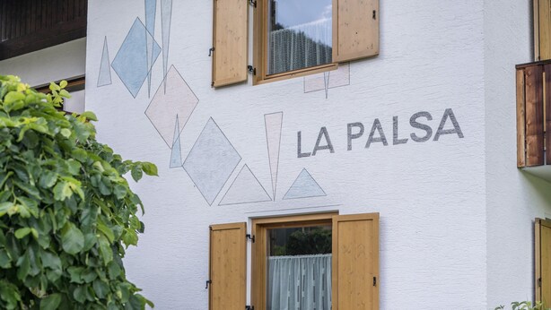 Un bâtiment orné de motifs géométriques sur les murs, doté de volets en bois et portant l’inscription « LA PALSA ».