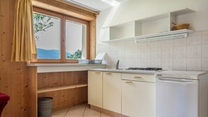 Une cuisine avec des meubles en bois, un lave-vaisselle blanc et une fenêtre donnant sur un paysage verdoyant.