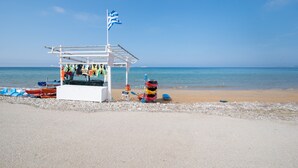 Un quiosco en la playa con una bandera, kayaks y una silla.