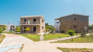 Un barrio residencial con edificios de piedra, un sendero pavimentado y una pequeña zona verde.