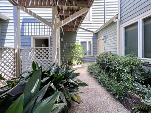 Relax on the covered patio surrounded by lush greenery and a charming pergola.