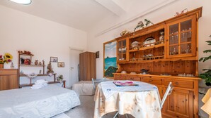 Un dormitorio con cama, una mesa con mantel, un aparador de madera con puertas de cristal y un cuadro en la pared.