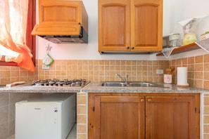 Una cocina con armarios de madera, una estufa a gas, un fregadero y un refrigerador Haier.