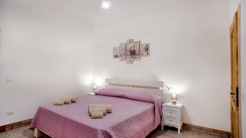 Un dormitorio con una cama, mesitas de noche, una obra de arte colgada en la pared y una puerta de madera.