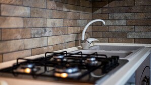 Una cocina con estufa a gas, un lavamanos blanco y salpicadero de azulejos.