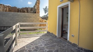 Un patio empedrado con un banco de madera, una pared amarilla y una puerta de entrada.