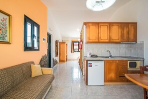 Una cocina compacta con muebles de madera, un refrigerador blanco y un microondas.