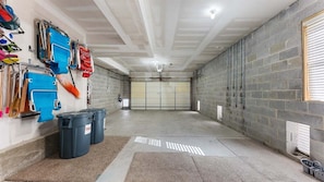 A clean, well-lit garage with a concrete floor, a garage door, and various tools and equipment on the walls.