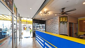 Een receptiegedeelte met een blauw en geel aanrecht, een plafondventilator en een behang met een patroon.