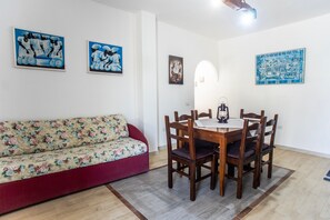 Un comedor con una mesa y sillas de madera, un sofá floral y obras de arte en las paredes.