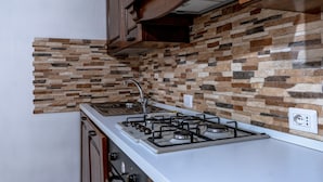Une cuisine équipée d’une cuisinière à gaz, de meubles en bois et d’un pare-feu en pierre.