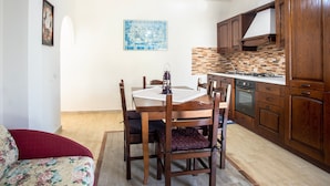 Un coin repas avec une table et des chaises en bois, une cuisine avec des meubles en bois et un dosseret carrelé.
