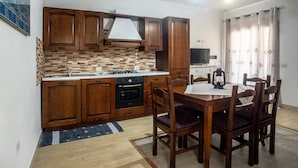 Une cuisine avec des meubles de rangement en bois, un pare-feu en carrelage, une table à manger avec des chaises et un luminaire suspendu.
