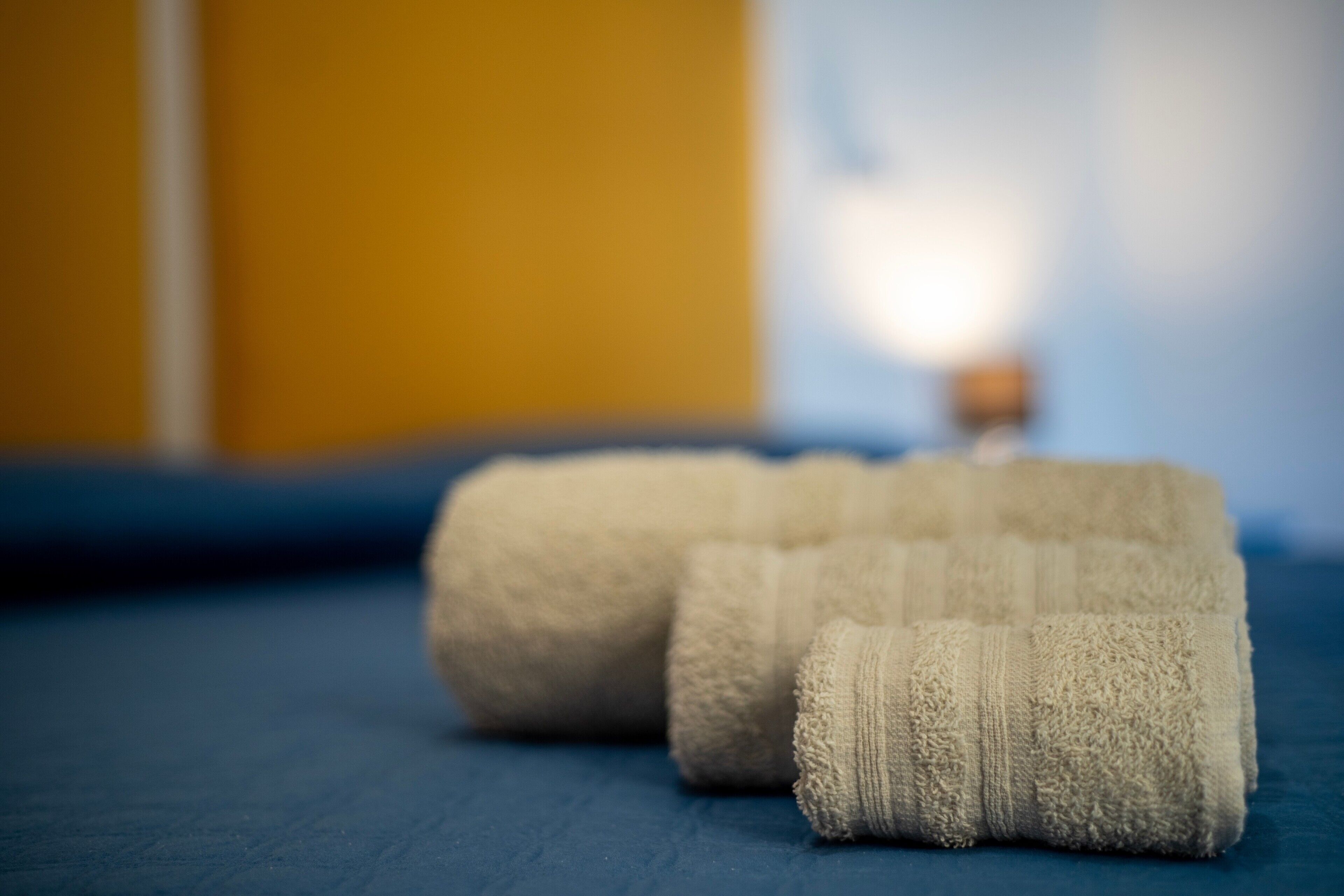 Two rolled towels on a blue surface.