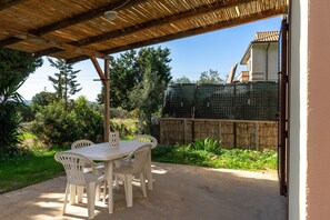 An outdoor patio with a table and chairs, a wooden pergola, and a view of a house and trees. - Villa "Orchidea" with Garden, Terrace, Balcony & Air Conditioning (Masainas)