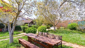 A wooden picnic table with benches in a garden with trees and a small building in the background. - Apartment 2155/53610 (Istria - Liznjan), 1700m from the beach (Liznjan)