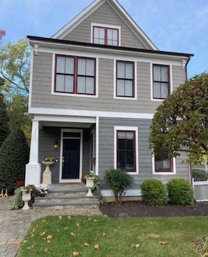 A two-story house with a front porch, a garage, and a well-maintained lawn.