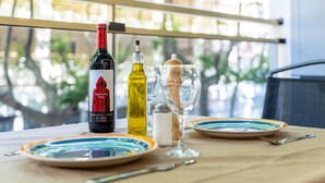 A table with a wine bottle, a glass, and plates, set on a balcony with a view of greenery. - Apartment 'Salou - 111' with Shared Pool, Wi-Fi and Air Conditioning (Salou)