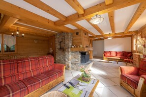 Un intérieur en bois avec une cheminée, des canapés à carreaux rouges et un mur en pierre.