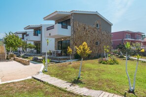 Una casa moderna de dos pisos amb façana de pedra, un balcó i un jardí ben cuidat.