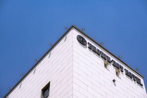 A hotel with a white facade and a clear blue sky in the background. - Brown Dot Hotel Gijang Station (Busan)