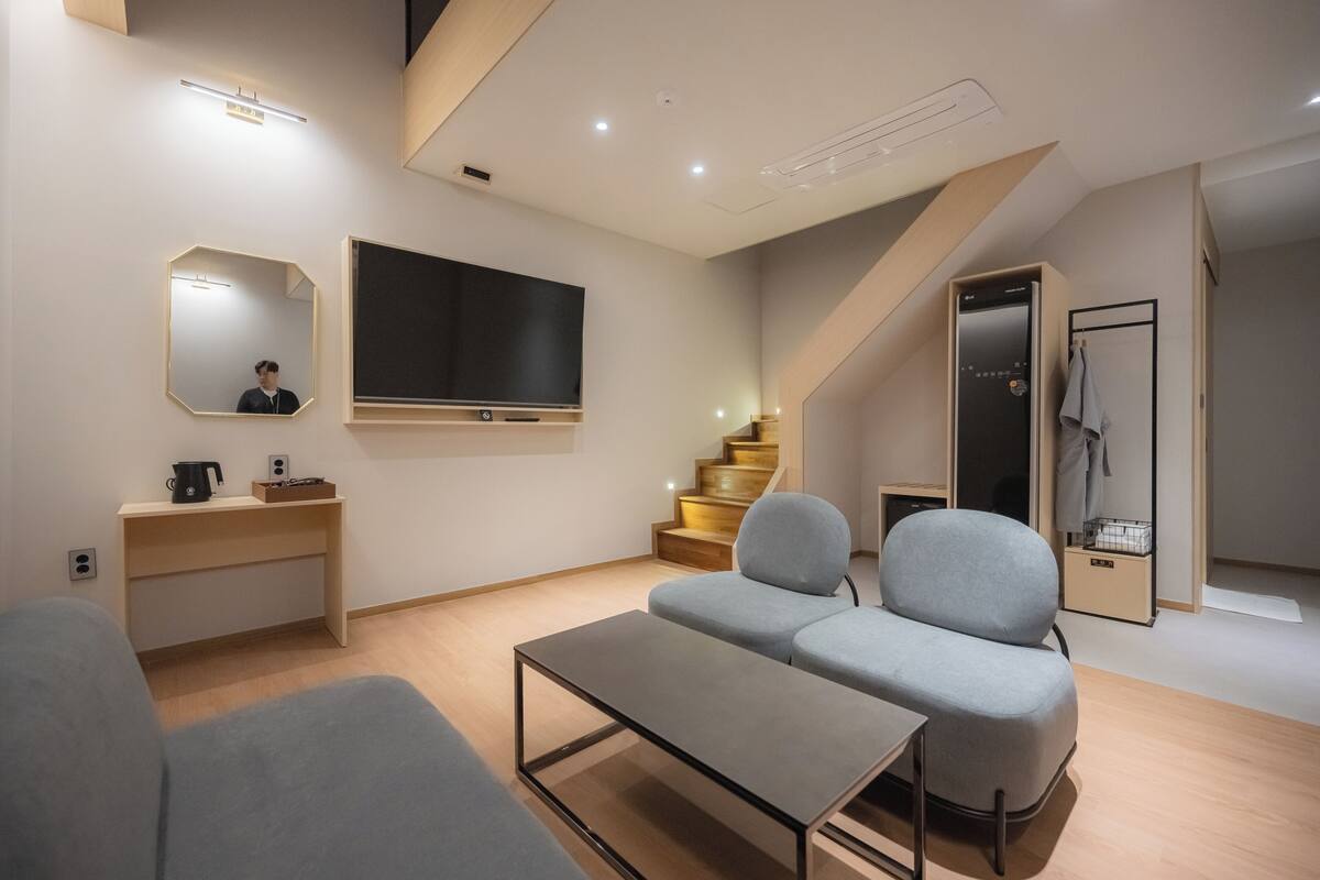 A modern living room with a sofa, a coffee table, a TV, and a staircase.