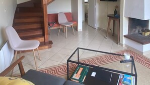 A living room with a staircase, a sofa, a coffee table with books, a TV, and a fireplace. - House with garden 800m from the 2 beaches of Saint Cast (Saint-Cast-le-Guildo)