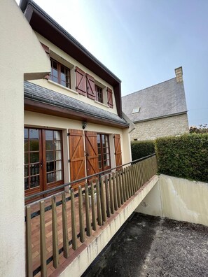 Une maison à deux étages avec un balcon et un mur en pierre.