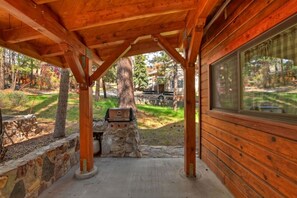 Un espacio al aire libre cubierto con pared de piedra, una parrilla y vista a una calle residencial.