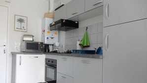 Moderni keittiö, jossa on valkoiset kaapit, mikroaaltouuni, kahvinkeitin ja leivänpaahdin.