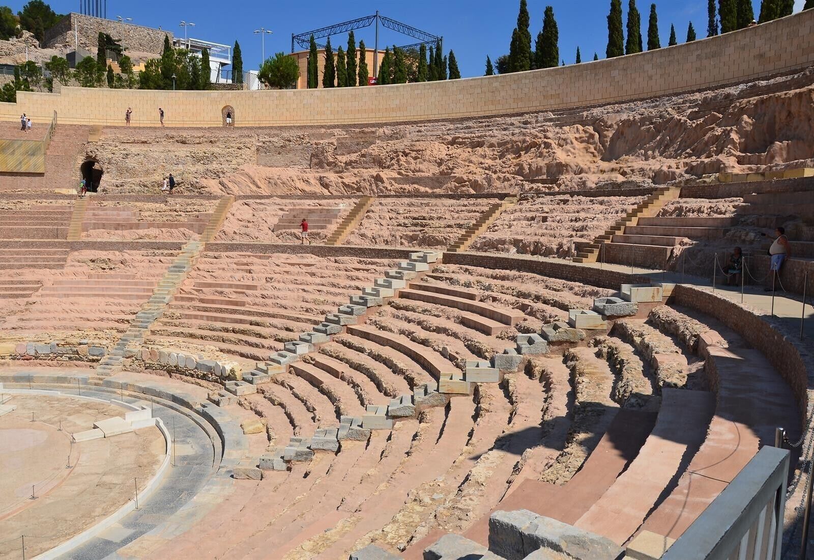 An ancient amphitheater with tiered seating and a stone wall.