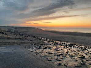 A beach with a wide sandy area and a rocky foreground.