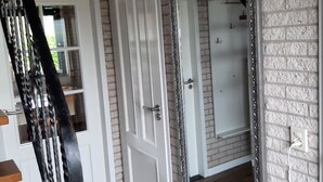 Ein Zimmer mit weißer Tür, einem großen Spiegel und einer Treppe mit schwarzen Geländern.