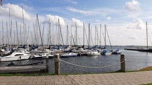 Ein Yachthafen mit mehreren Segelbooten, eine Rasenfläche im Vordergrund und ein klarer Himmel.
